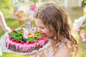 Mädchen nehmen beißen von aus Stück von Glückwunsch Kuchen. Geburtstag und Herzliche Glückwünsche Konzept. foto