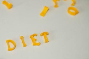 Wort Diät besteht von essbar Briefe. Pasta Diät Lebensmittel. Pasta im bilden von Briefe auf grau Hintergrund. richtig Ernährung Konzept. foto