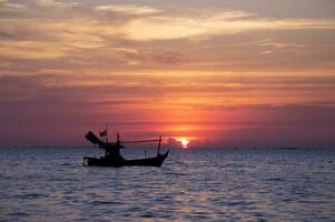 Silhouette von Fischer Boot mit während Sonnenuntergang im Thailand foto