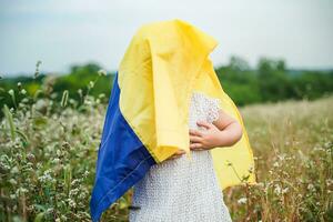 Flagge von Ukraine im Hände von lächelnd wenig Mädchen. glücklich Kind trägt Gelb / Blau Flagge. Tag von Ukraine Unfähigkeit. selektiv Fokus auf Flagge. foto