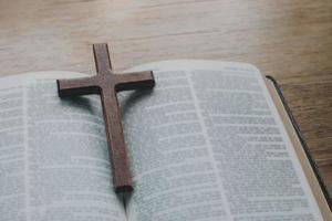 Nahaufnahme der einfachen Holzkette des christlichen Kreuzes auf der Bibel? foto