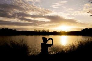 Silhouette von Frau nehmen Bild beim das See foto