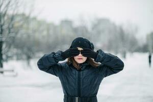 Mädchen Dekade geschlossen Augen mit händisch Hintergrund von Winter Landschaft. Kind tut nicht wollen zu sehen. foto