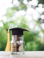 Glas Flasche mit Abschluss Hut. das Konzept von Speichern Geld zum Ausbildung, Schüler Darlehen, Stipendium, Unterricht Gebühren im Zukunft foto