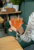 alkoholisch Cocktail im Hand Über ein hölzern Tisch. Trinken Cocktail im Cafeteria Konzept. foto