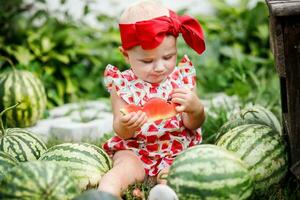 Porträt von Kleinkind Mädchen genießen ein Wassermelone. Baby Essen ein Wassermelone Scheibe foto