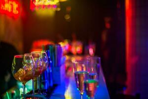 Wein Brille im ein Restaurant beim ein Party. Licht Musik- und Laser- Show im ein Bar oder Cafe. Neon- Beleuchtung beim ein Restaurant Party. Bar Tabelle Rahmen zum alkoholisch Getränke. foto