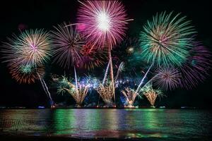 erstaunliches schönes buntes Feuerwerk in der Feiernacht, das am Meeresstrand mit mehrfarbiger Reflexion auf dem Wasser gezeigt wird foto