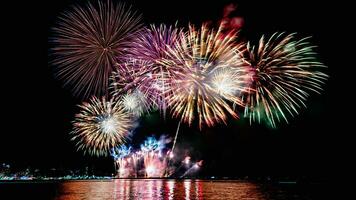 erstaunliches schönes buntes Feuerwerk in der Feiernacht, das am Meeresstrand mit mehrfarbiger Reflexion auf dem Wasser gezeigt wird foto