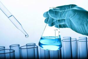 Flasche im Wissenschaftler Hand mit Labor Glaswaren Hintergrund foto