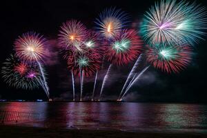 erstaunliches schönes buntes Feuerwerk in der Feiernacht, das am Meeresstrand mit mehrfarbiger Reflexion auf dem Wasser gezeigt wird foto