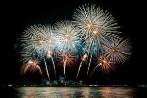 erstaunliches schönes buntes Feuerwerk in der Feiernacht, das am Meeresstrand mit mehrfarbiger Reflexion auf dem Wasser gezeigt wird foto