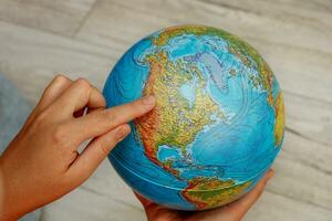 Frau Hand zeigt an Norden Amerika auf das Globus foto