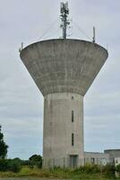 ein Beton Wasser Turm mit ein groß Antenne auf oben foto