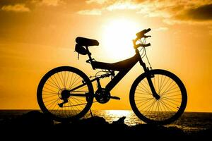 ein Fahrrad ist silhouettiert gegen das Sonne beim Sonnenuntergang foto