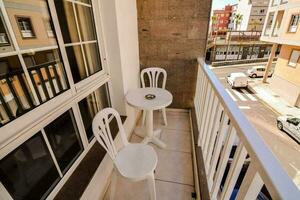 ein Balkon mit Weiß Stühle und Tabelle über ein Straße foto