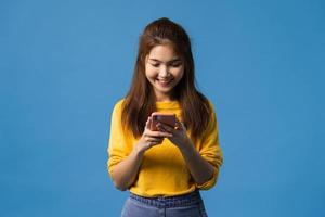 asiatische Dame mit Telefon mit positivem Ausdruck auf blauem Hintergrund.
