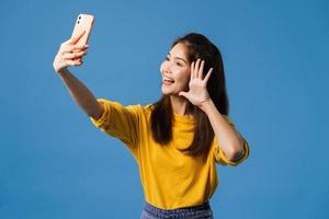 asiatische Frau, die selfie Foto auf Smartphone auf blauem Hintergrund macht.