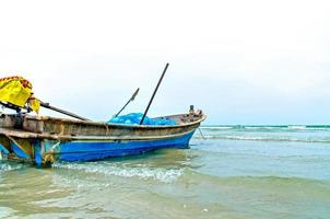 der Sandstrand und das Meer mit dem Boot, das direkt am Strand geparkt ist. foto