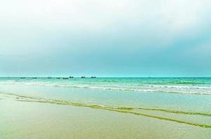 der Blick auf den Sandstrand und die Meereswelle mit Felsen und Riff am Morgen foto