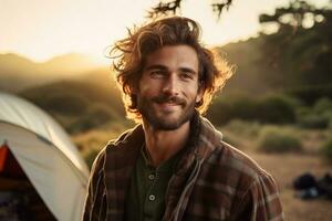 Porträt von Mann suchen beim Kamera während in der Nähe von Camping Zelt beim Sonnenuntergang ai generiert foto
