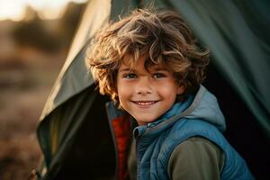 Porträt von ein süß Junge suchen beim Kamera während in der Nähe von seine Zelt im Natur ai generiert foto