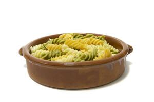 Spiral- Pasta von drei Farben, serviert im ein Lehm Schüssel. isoliert auf ein Weiß Hintergrund. Vegetarier Essen Konzept. foto