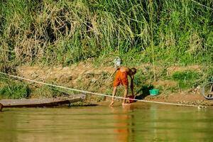 ein Mann ist Waschen seine Kleider im das Fluss foto