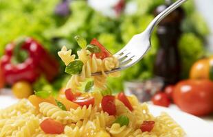 Teller von gekocht Italienisch Fusilli Pasta mit Tomaten und Basilikum Blätter foto