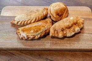 abwechslungsreiche argentinische Empanadas mit verschiedenen Füllungen auf einem Holzbrett foto
