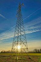 ein schön Sonnenuntergang hinter ein elektrisch Turm foto