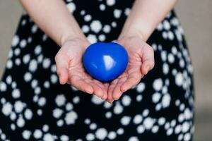 Blau Herz im das Hände von ein Frau im ein Polka Punkt Kleid foto