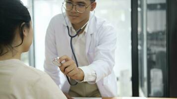 jung Arzt ist mit ein Stethoskop Hör mal zu zu das Herzschlag von das geduldig. foto