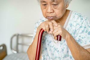 asiatisch Alten Behinderung Frau halten wackeln Stock, Holz Stock, runden handhaben, Gehen Hilfe zum Hilfe zu gehen. foto