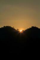 Die Sonne geht morgens und abends auf und unter, und die Bäume sind schwarz beschattet - orangefarbener Himmel und Wolken. warm, romantisch und herrlich schön, es sieht warm und reisend aus. foto