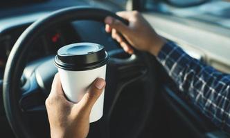 Mann mit Kaffee-Pappbecher im Auto foto