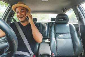 junger asiatischer Mann mit Smartphone beim Autofahren foto