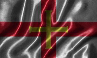 Tapete von Guernsey-Flagge und wehende Flagge von Stoff. foto