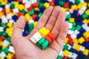 Hand mit bunten Plastikbausteinen auf buntem Hintergrund foto