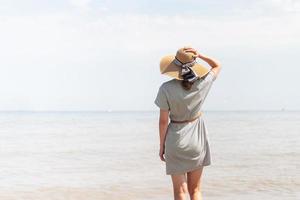 Frau in Sommerkleidung steht auf einem Pier, Meer im Hintergrund foto