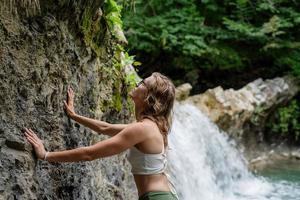 junge sexy Frau im Badeanzug genießt den Wasserfall