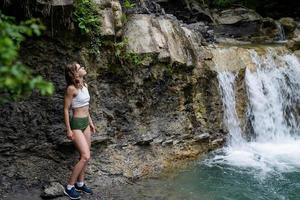 junge sexy Frau im Badeanzug genießt den Wasserfall