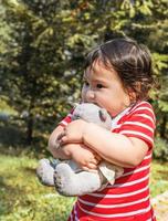 asiatisches Baby, das ihr Spielzeug umarmt und im Freien spazieren geht