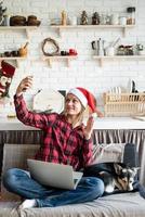glückliche Frau in Weihnachtsmütze grüßt ihre Freunde im Video-Chat auf dem Laptop foto