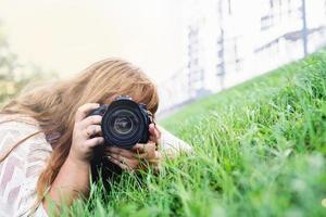 Porträt einer übergewichtigen Frau, die im Park Fotos mit einer Kamera macht