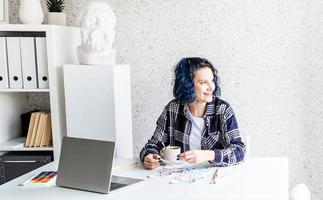 Designerin, die in ihrem Studio mit Farbpaletten und Laptop arbeitet