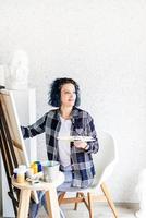 Kreative Frau mit blau gefärbten Haaren malt in ihrem Atelier foto