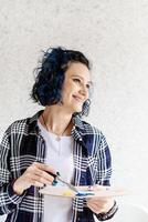 Kreative Frau mit blau gefärbten Haaren malt in ihrem Atelier foto