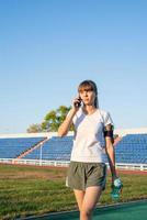 junge Sportlerin telefoniert im Stadion foto