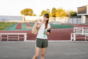 Teenager-Mädchen, das nach dem Training mit der Papiertüte im Stadion spazieren geht foto